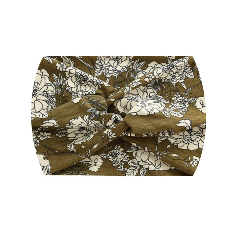 A close-up of a brown and cream floral print fabric tied into a wide knotted headband.