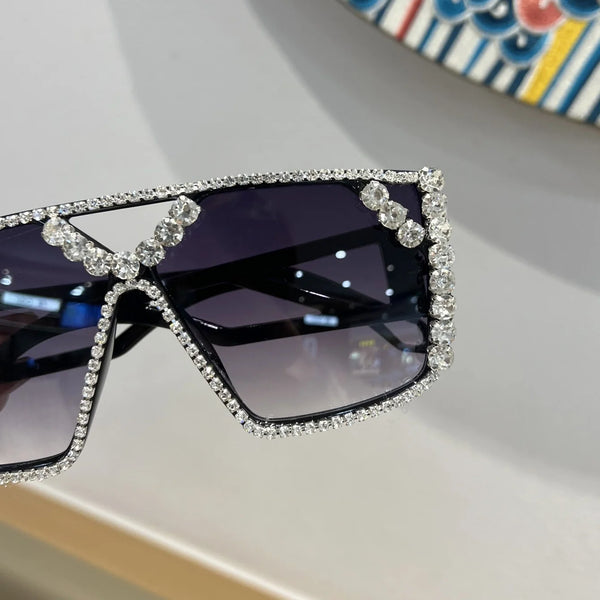 A pair of purple-tinted fashion sunglasses adorned with sparkling rhinestones and geometric detailing.