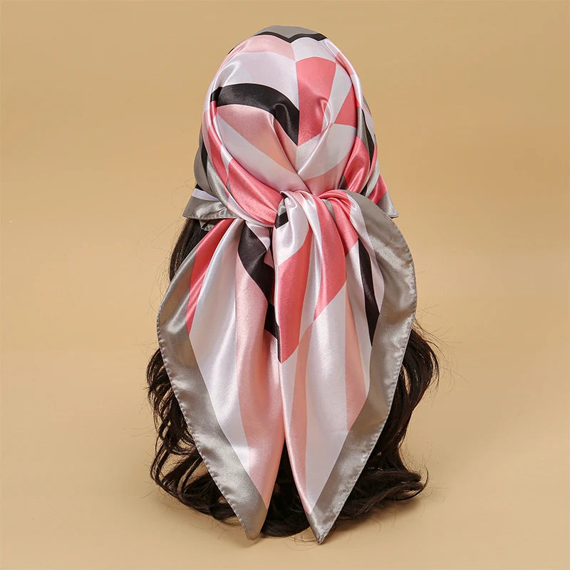 A pink, black, and silver satin square scarf tied in a bow, suitable for hijab or hair.