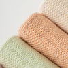 A stack of four pastel colored non-slip yoga socks in peach, pale green, and pink tones.