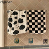 A black and white cow print face towel hanging on a tiled wall.