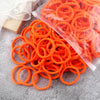 A pile of bright orange elastic hair bands in various sizes and colors.