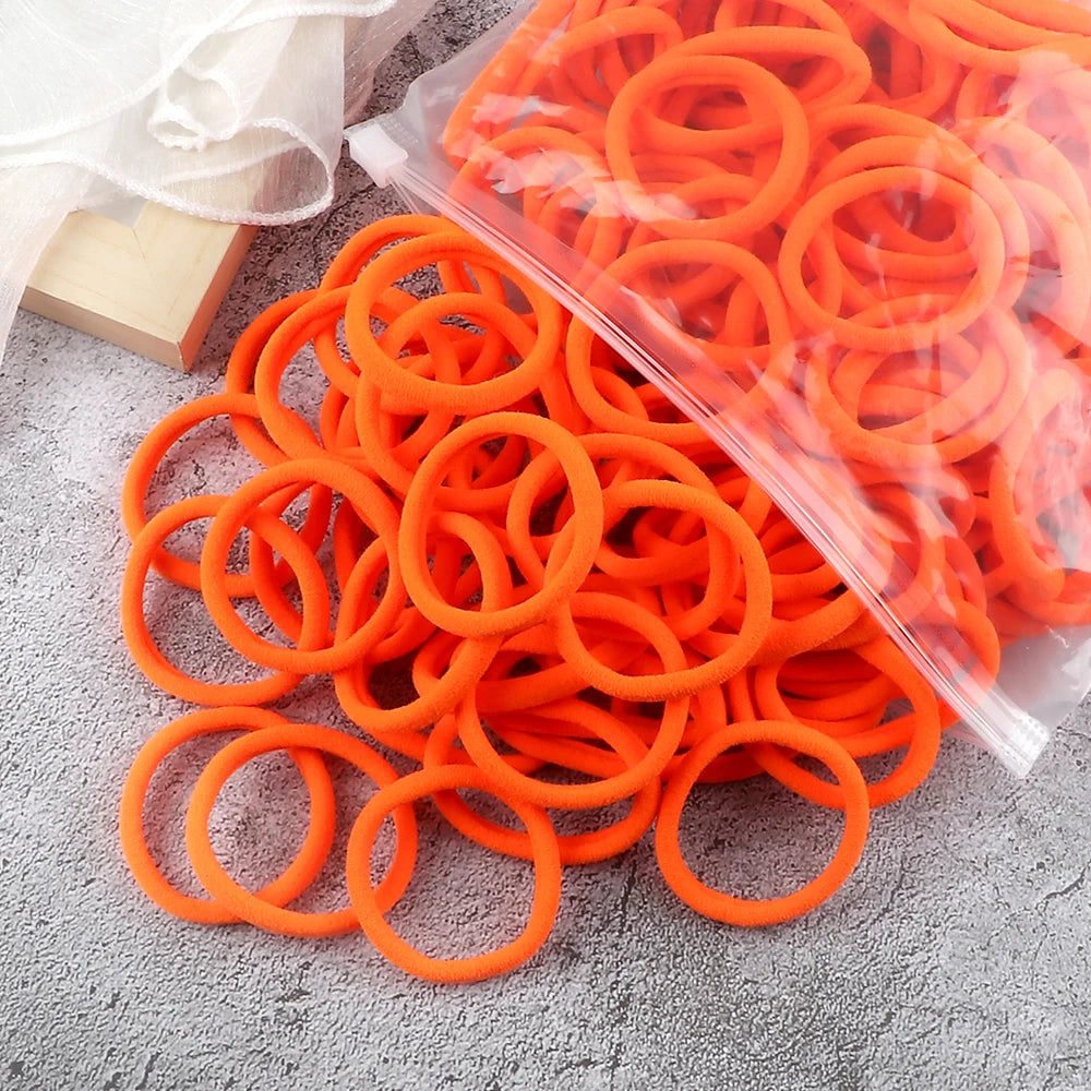 A pile of bright orange elastic hair bands in various sizes and colors.