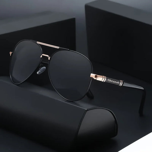 Un par de gafas de sol polarizadas negras con detalles dorados, descansando sobre una superficie oscura.