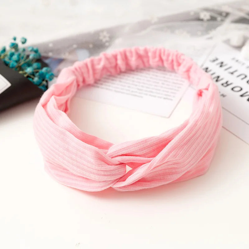 Pink bohemian chiffon fabric headband tied in a knot resting on a white surface.