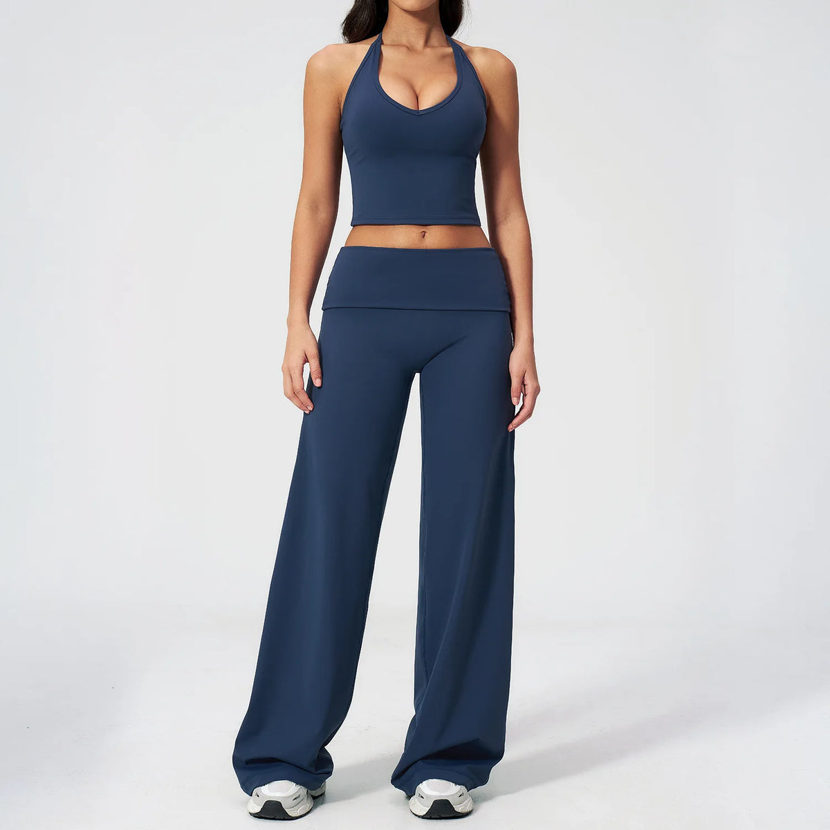 A woman wearing a navy blue women's premium fitness tracksuit consisting of a sports bra top and matching long pants.