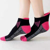 Ein Paar rosa und schwarze feuchtigkeitsableitende Sportsocken mit gerippter Struktur auf einem Fuß.