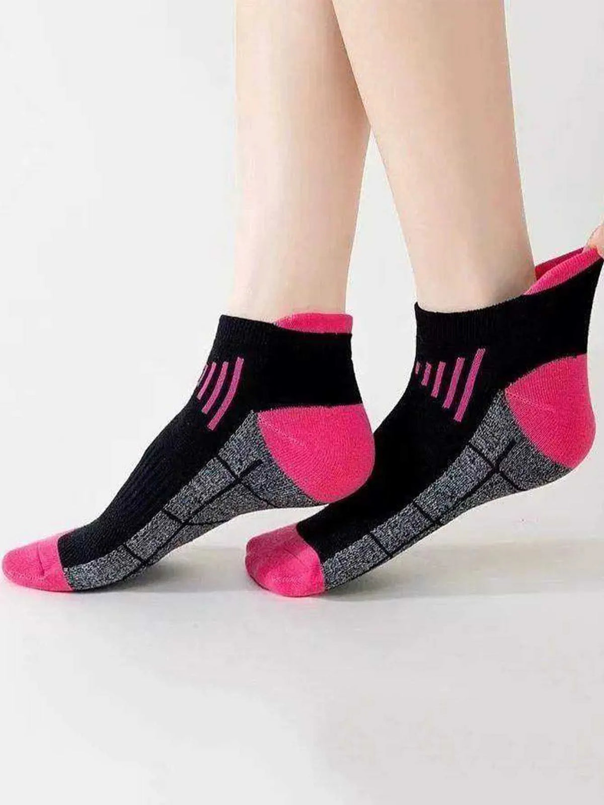 Ein Paar rosa und schwarze feuchtigkeitsableitende Sportsocken mit gerippter Textur auf einer weißen Oberfläche.