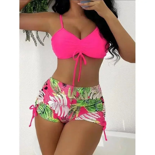 A woman models a bright pink crop top and matching floral print high-waist bikini bottoms.
