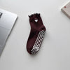 A pair of dark brown yoga socks with silver embroidery and white polka dots resting on a white surface.