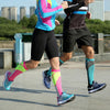 Two people running outdoors wearing brightly colored compression socks and athletic clothing.