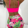 A woman models a bright pink floral print two-piece high-waist bikini set from the back view.