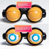 A pair of black novelty glasses with yellow lenses and a pink sign instructing the user to keep their mouth still and open th