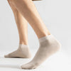 A close-up of a pair of beige men's combed cotton socks being worn on a leg.