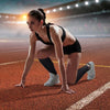 A female athlete in a black sports bra and shorts is performing a stretch on an orange track, demonstrating calf compression 