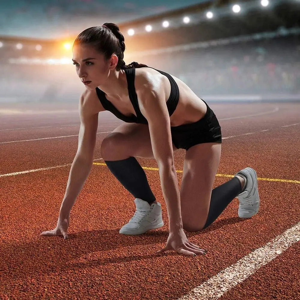 A female athlete in a black sports bra and shorts is performing a stretch on an orange track, demonstrating calf compression 