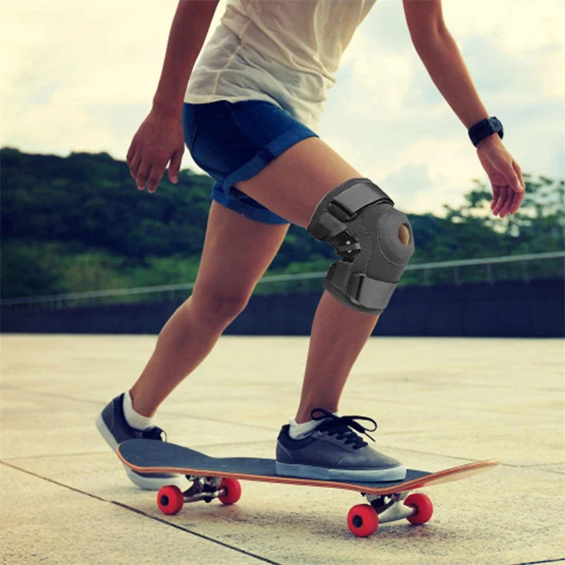 Eine Person mit einem grauen, geknickten Knieschiene fährt Skateboard auf Beton.