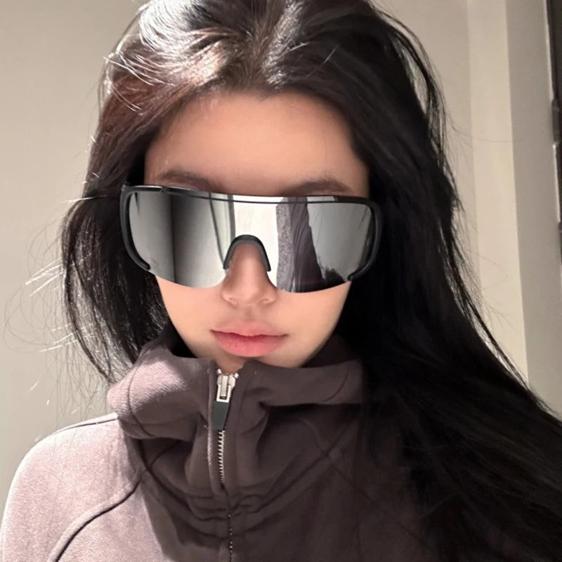 امرأة ترتدي نظارات سباق عاكسة قديمة ومعطف سحاب بني داكن.