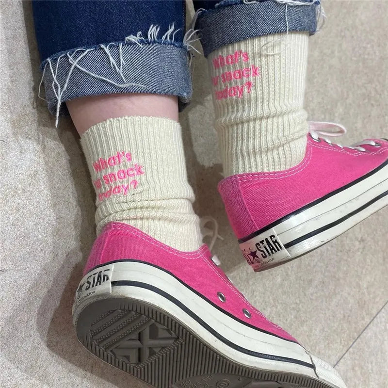 A pair of pink Converse sneakers worn with cream embroidered cotton socks.