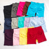 Collection de shorts de yoga sans couture à taille haute dans diverses couleurs vives et sourdes, disposés sur une surface bl