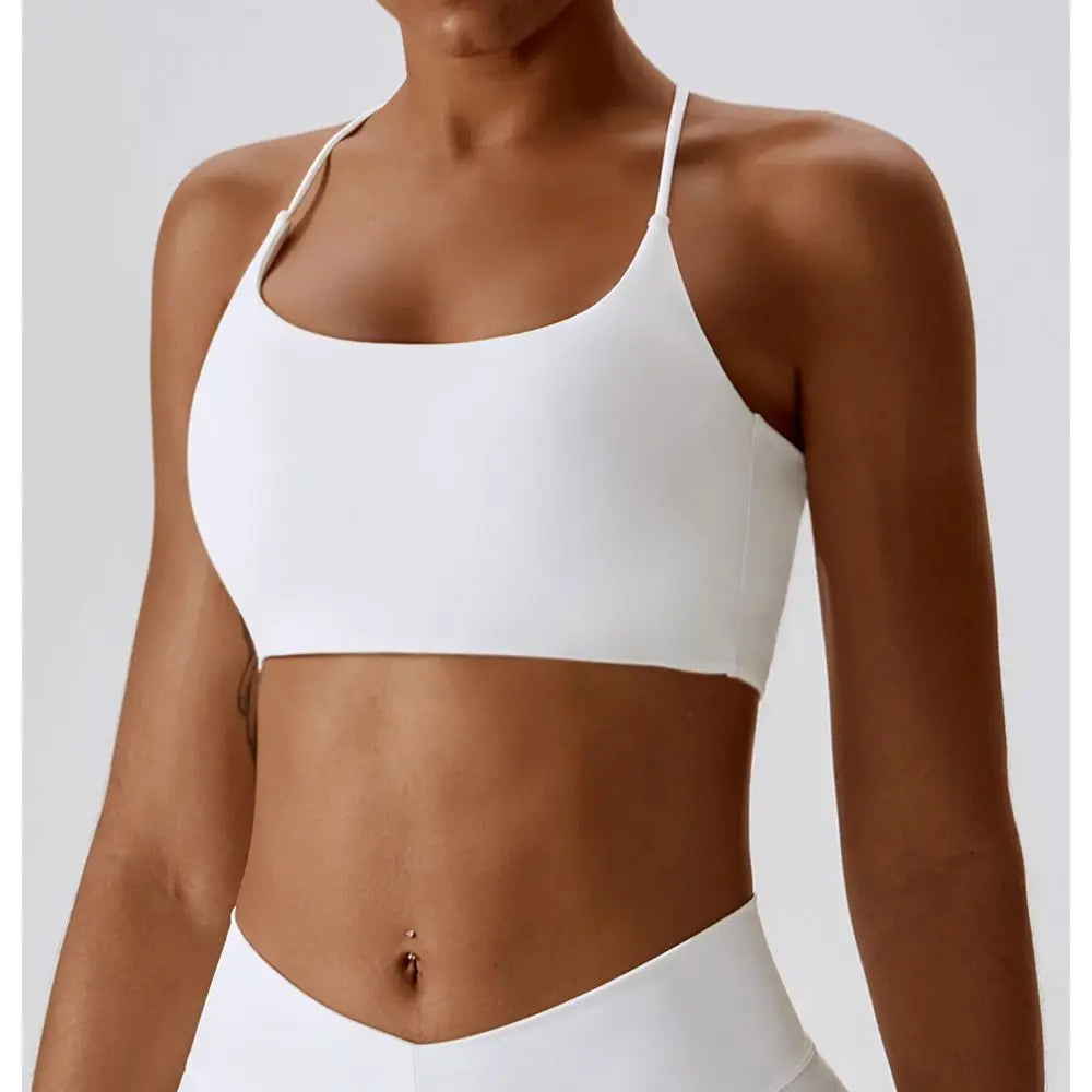 Modelo vistiendo un sujetador deportivo en forma de U blanco y la parte inferior a juego para fitness o yoga.