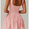 Model trägt ein pinkes Performance-Tenniskleid mit ärmellosem Oberteil und ausgestelltem Rock, von hinten gezeigt.