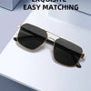 Gold-rimmed black square sunglasses resting on a white surface.