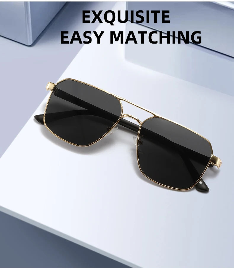 Gold-rimmed black square sunglasses resting on a white surface.