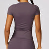 A woman wearing a mauve breathable yoga and fitness t-shirt from the back view.
