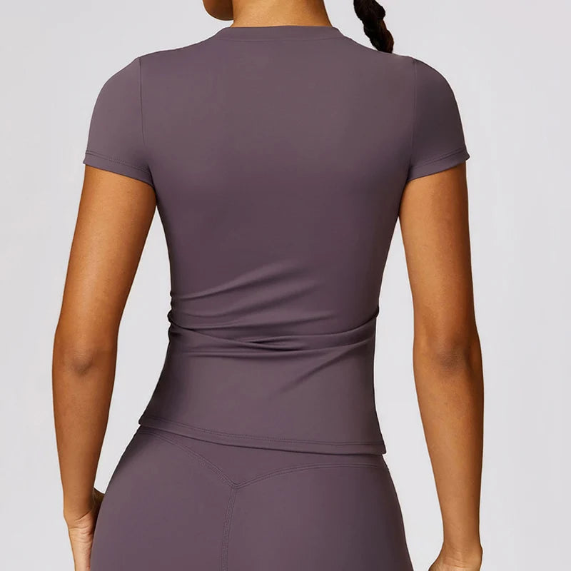A woman wearing a mauve breathable yoga and fitness t-shirt from the back view.