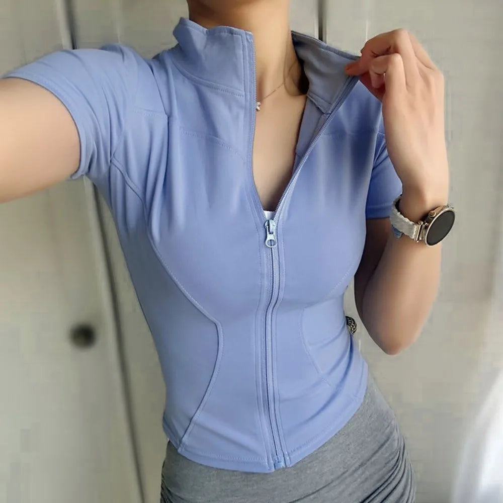 A woman wearing a light blue, long-sleeved sports yoga top with a quarter zip collar and fitted design.