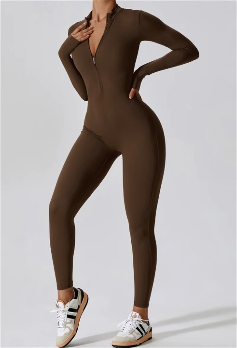 Model in a brown, long-sleeved half-zip yoga jumpsuit and white sneakers.