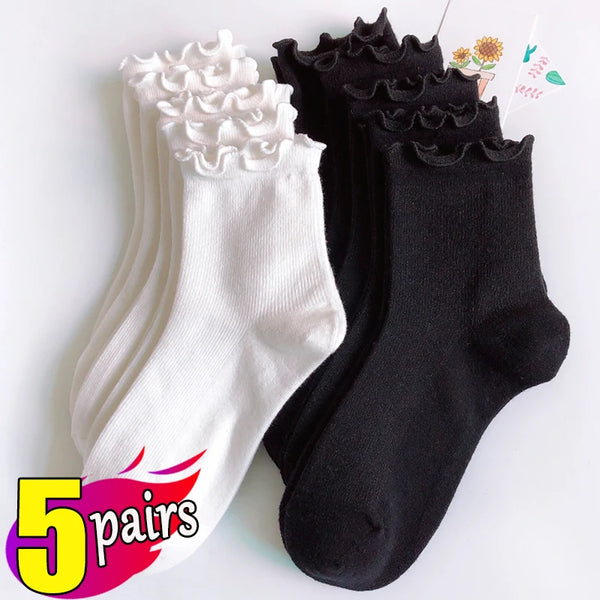 A stack of five pairs of white and black cotton ruffle ankle socks displayed on a white background.