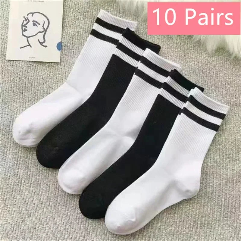 Ten pairs of black and white striped casual socks for men and women displayed on a light gray fabric.