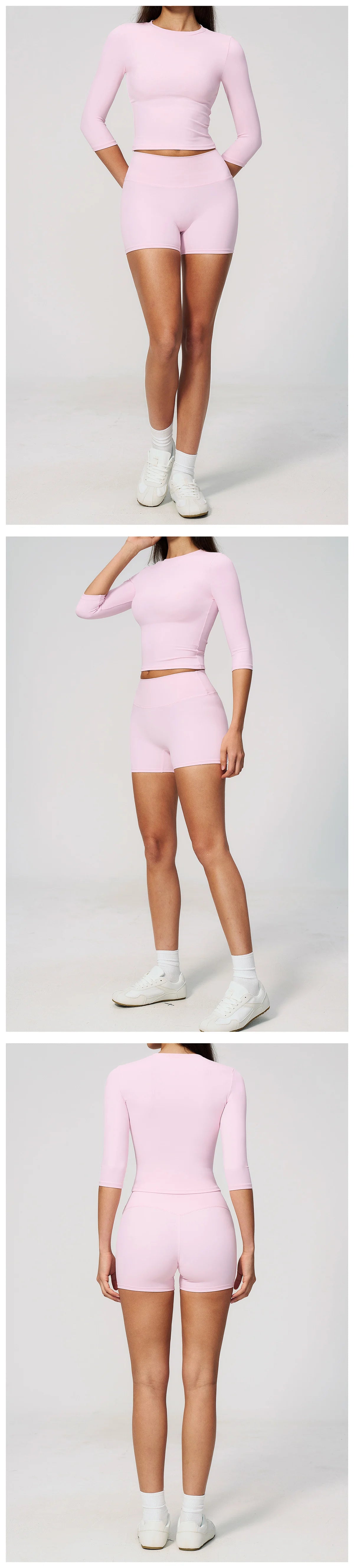 A woman models a pink two-piece yoga and fitness leggings set, consisting of a long-sleeved top and short bottoms.