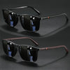 A pair of black vintage square sunglasses with dark lenses and brown accents are displayed on a dark surface.