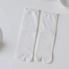 Pair of white knit crew socks with ruffle cuffs lying on a white surface.