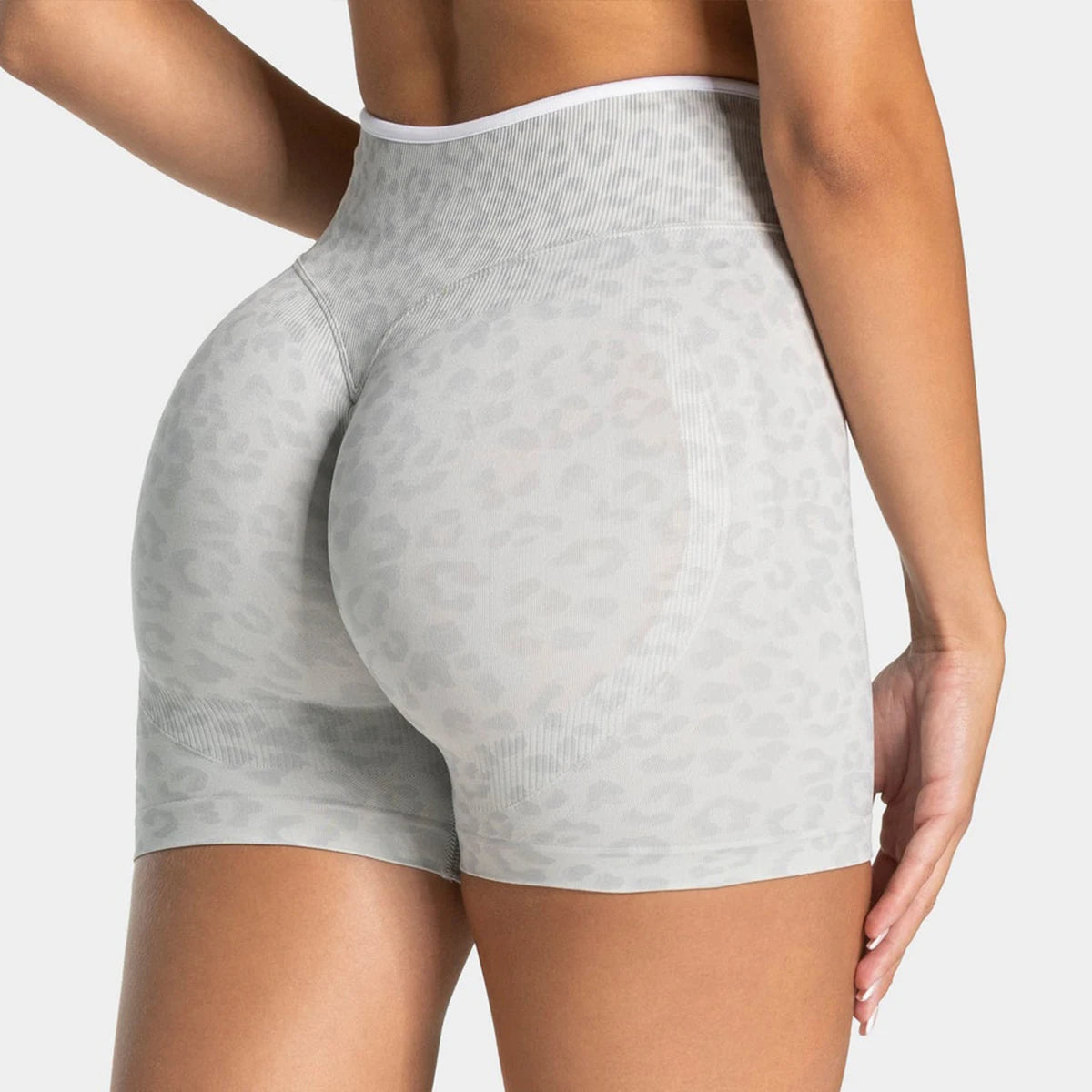 A woman is modeling leopard print seamless yoga shorts in a light gray color.