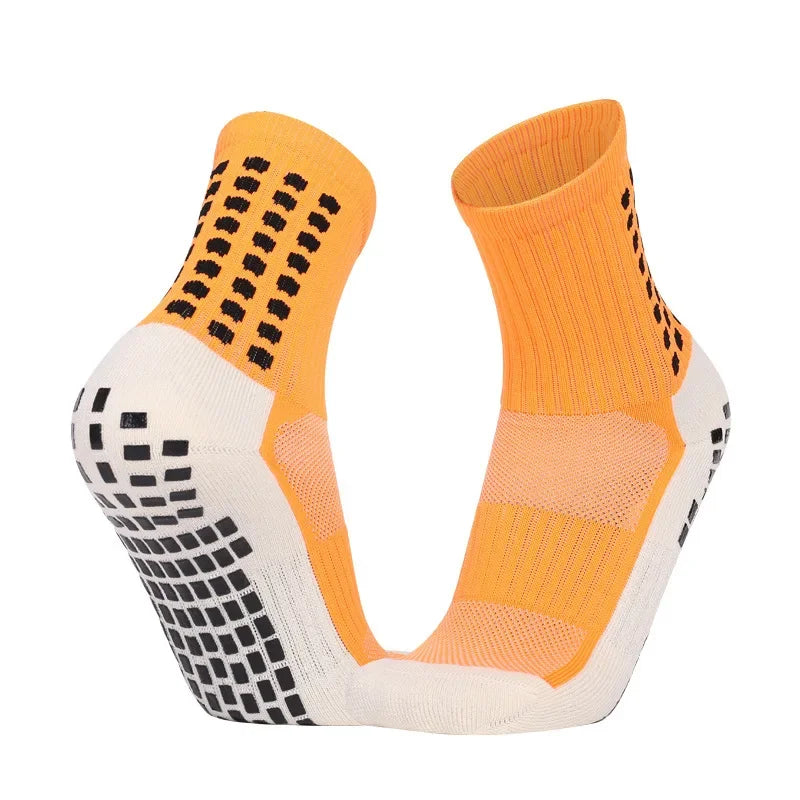 A pair of orange and white performance sports grip socks shown from the side.