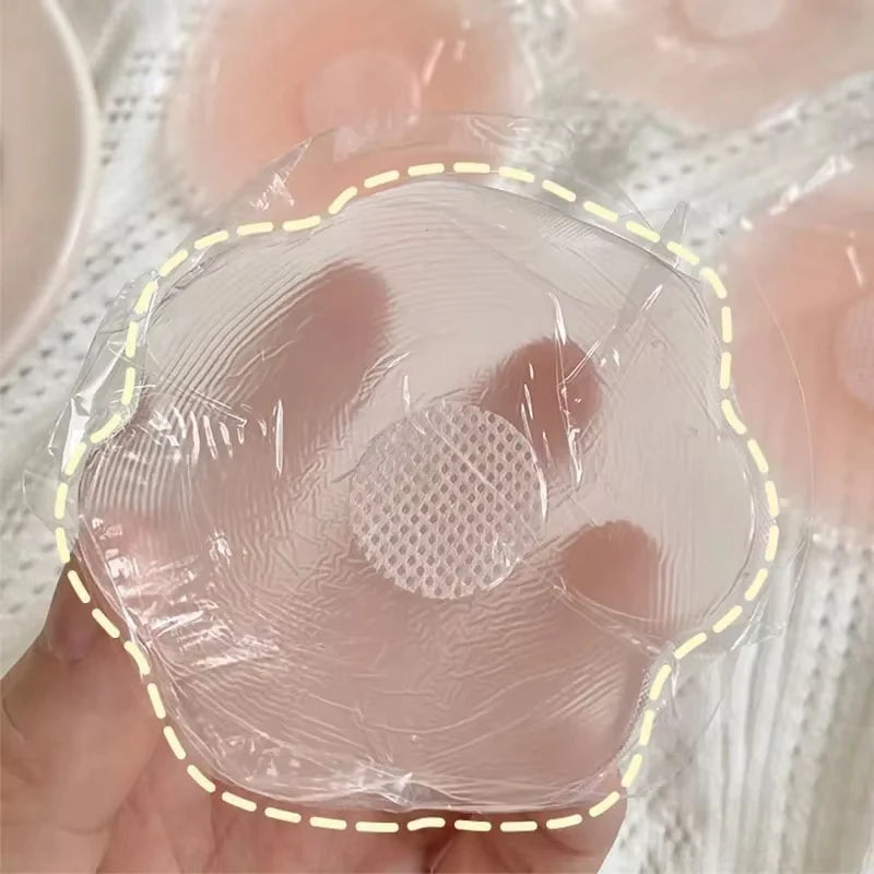 Une main tient une cacheoire silicone réutilisable pour bonnets de soutien-gorge sur un fond rose clair.