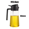 A black glass oil sprayer bottle with a handle and a spout, filled with yellow oil.