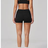A woman models a black two-piece yoga and sports tracksuit set consisting of a cropped top and shorts.