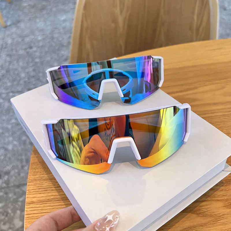 A pair of iridescent blue and purple cycling sunglasses resting on a white box on a wooden table.