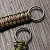 A close-up of a multi-tool keychain featuring a green and red braided cord attached to two black rings.