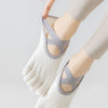 A close-up of a person wearing light gray five-finger invisible yoga and fitness socks on their foot.