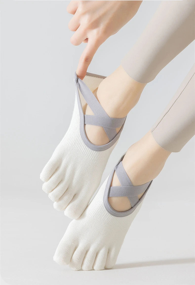 A close-up of a person wearing light gray five-finger invisible yoga and fitness socks on their foot.