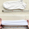 A white women's thin cotton no-show sock laid flat next to a ruler for size reference.