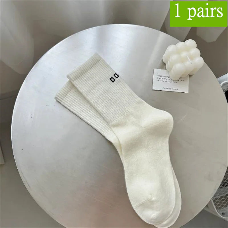 Ein Paar weiße atmungsaktive, rutschfeste Yoga- und Fitnesssocken auf einem runden Tisch.