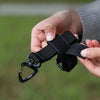 A hand holds a black tactical nylon glove hook for storage and climbing.