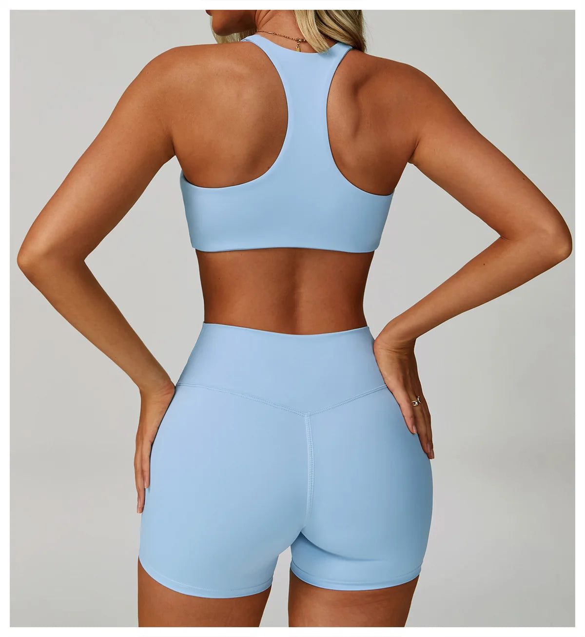 A woman models a light blue padded sport yoga bra and matching shorts from the back view.